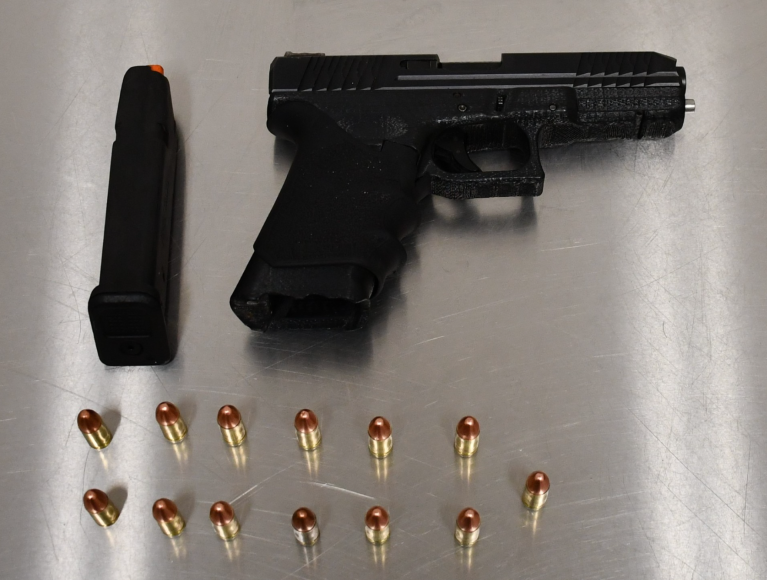 A suspected 3D printed handgun and some bullets on a steel table.